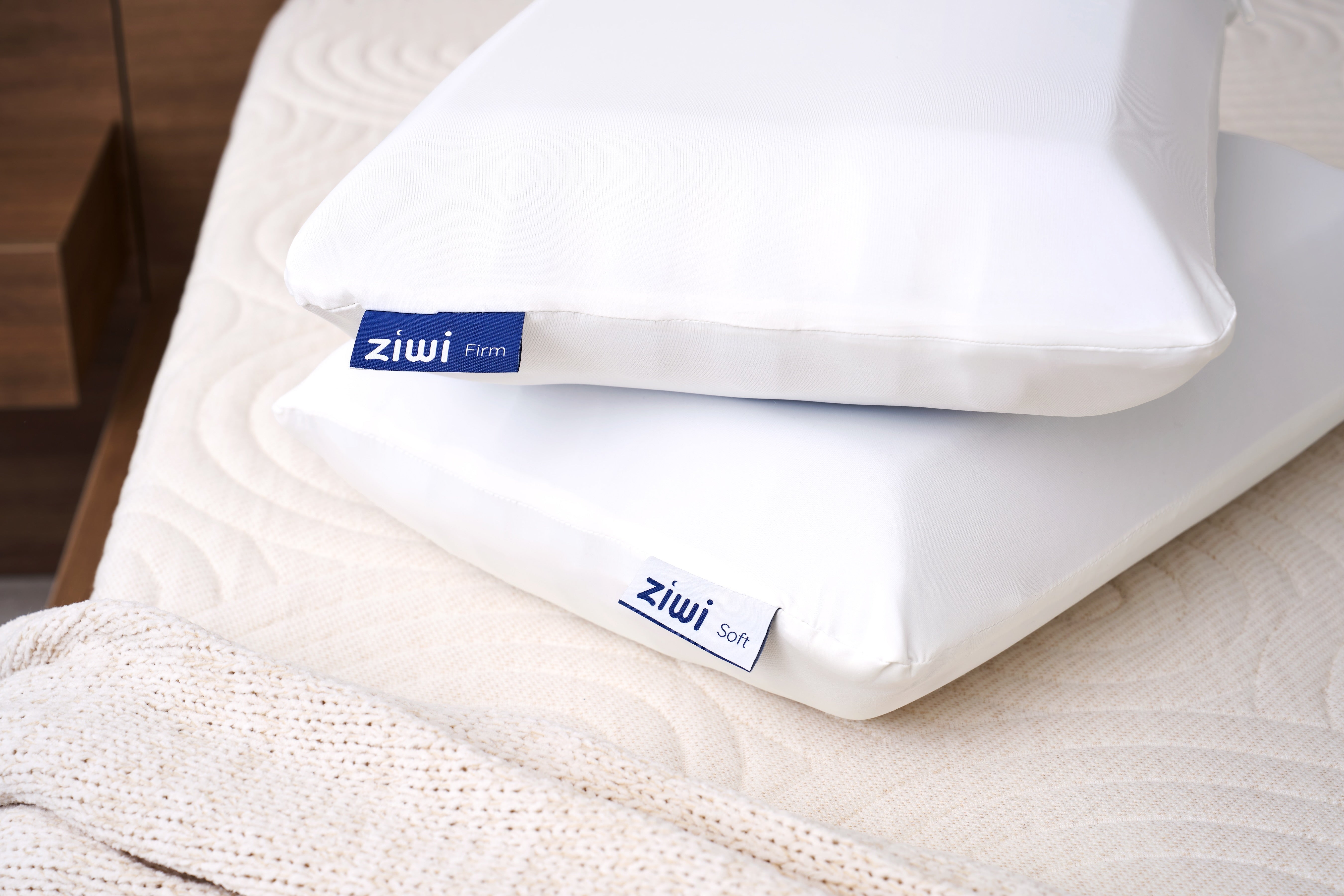 Two white pillows with 'ziwi' branding on a bed, showing that the pillow can be flipped