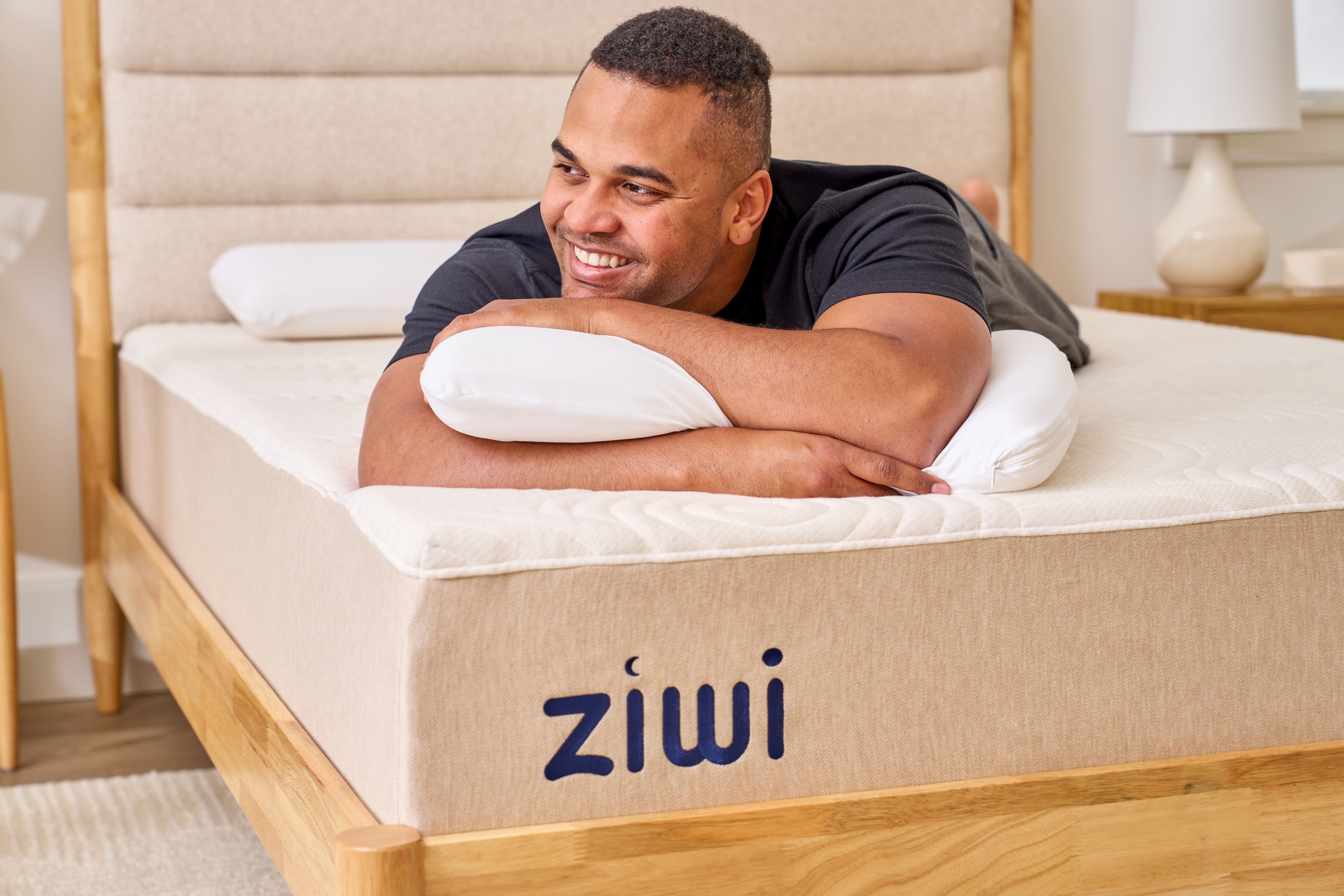 Man lying on a Ziwi mattress in a bedroom setting