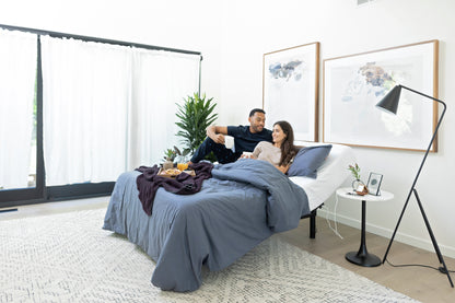 Two people sitting on a bed in a modern bedroom with decor elements. Adjustable Base.